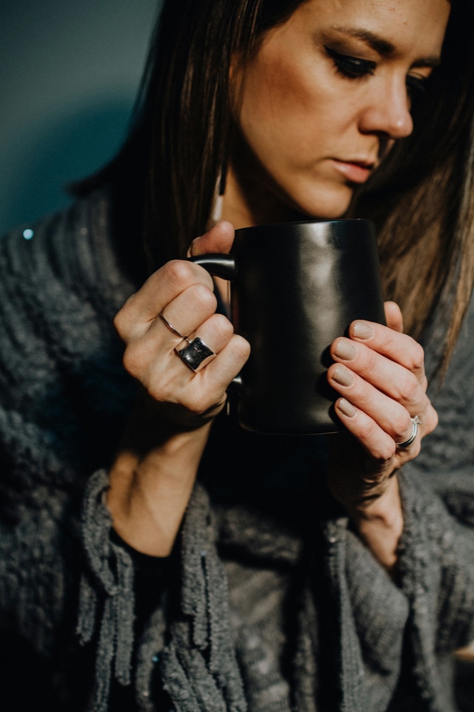 Warm hands holding a black ceramic mug — comforting wellness imagery